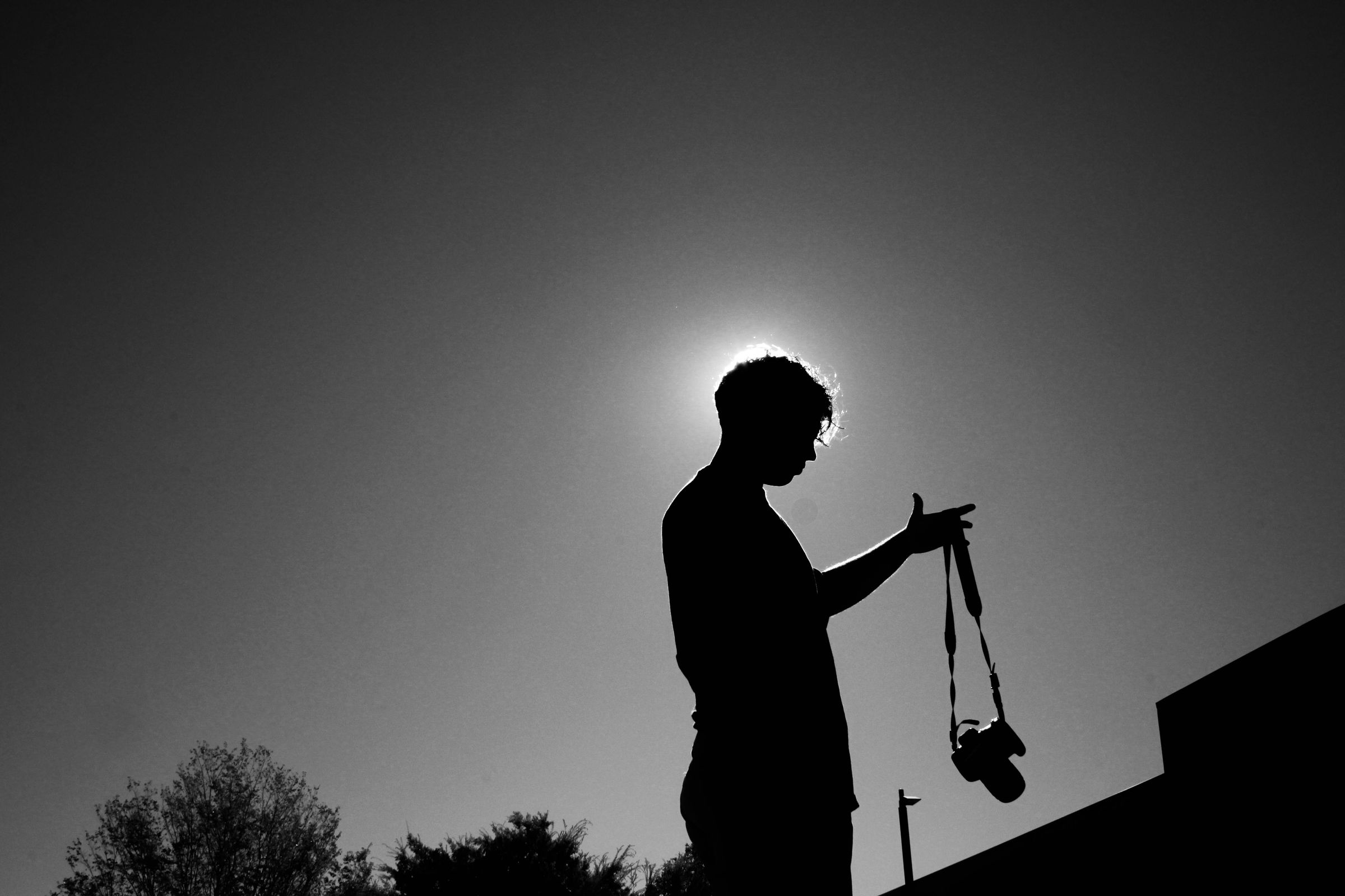 Silhouette of the photographer holding a camera against the sun